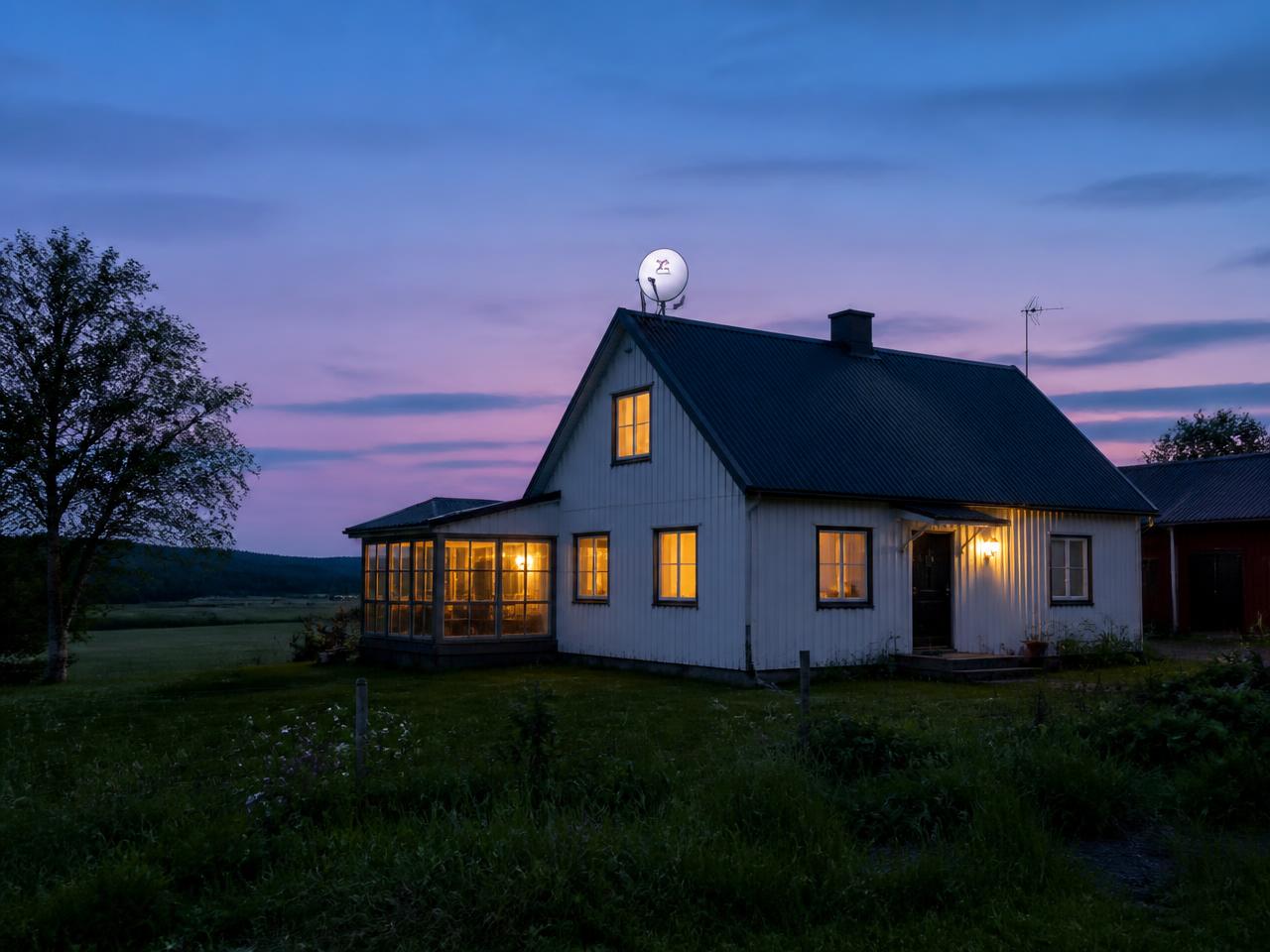 Casa rural ao anoitecer com antena de satélite no telhado